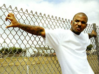 The Game leaning on a fence
